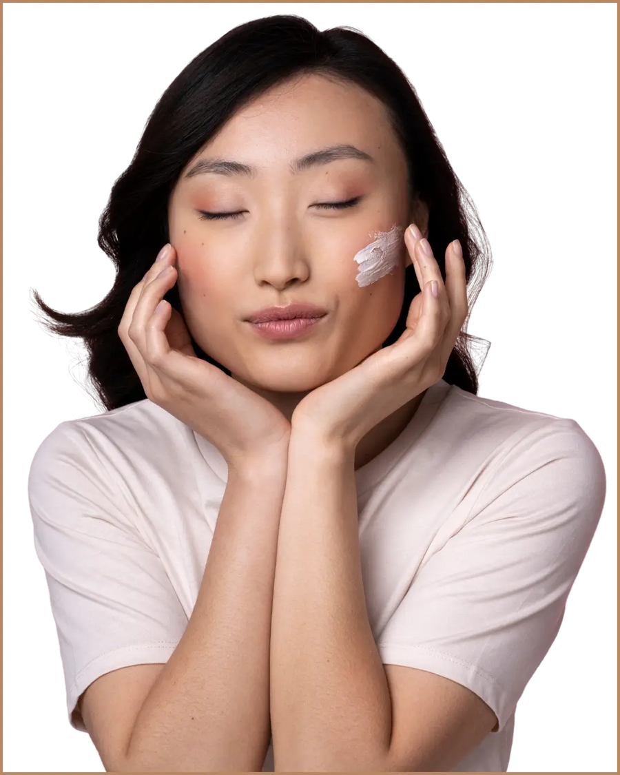 Woman applying cream to her face with a neutral background